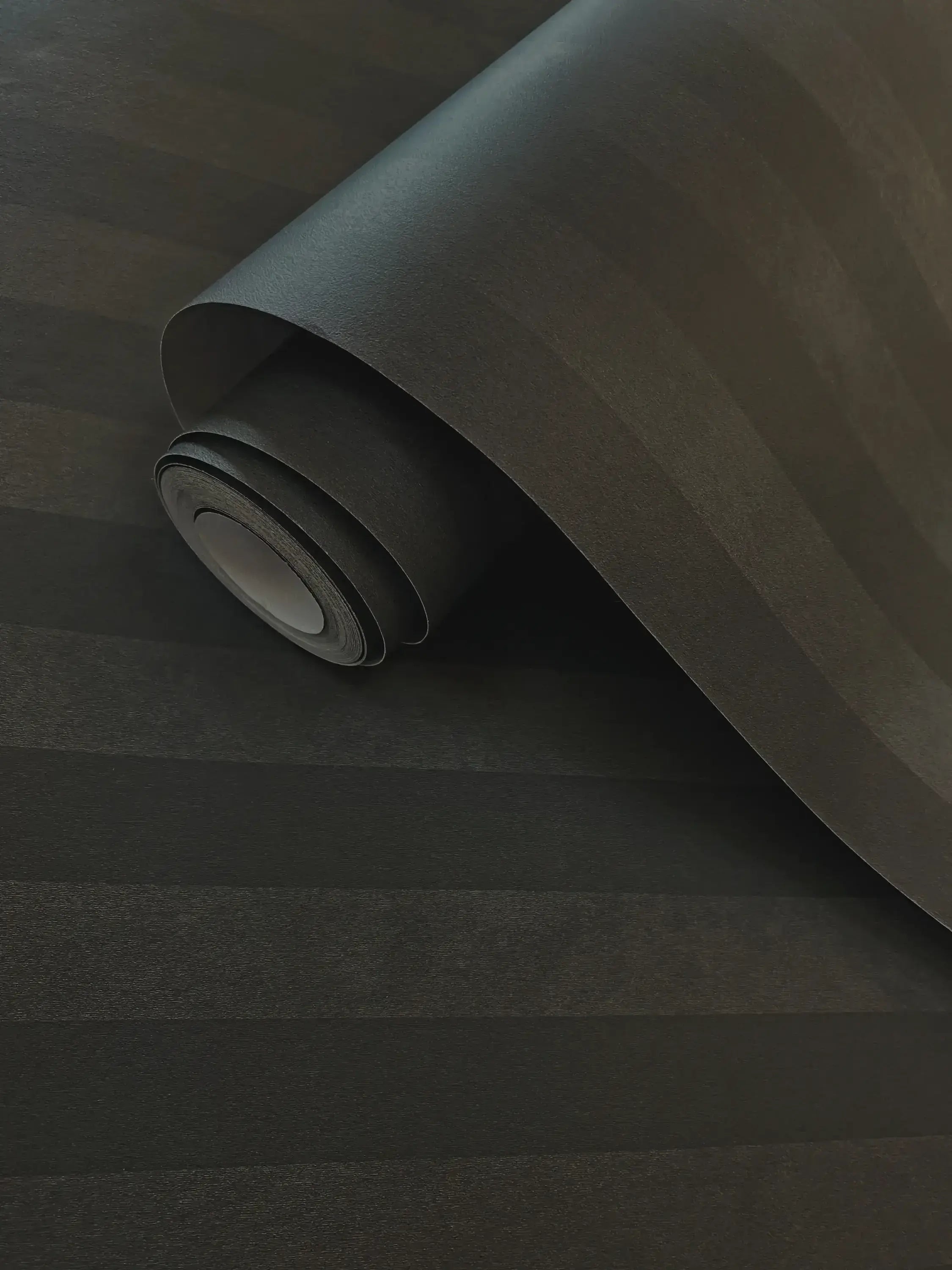 Nærbillede af en udrullet Aquila - Charcoal tapetrulle med synlige teksturer og farver.