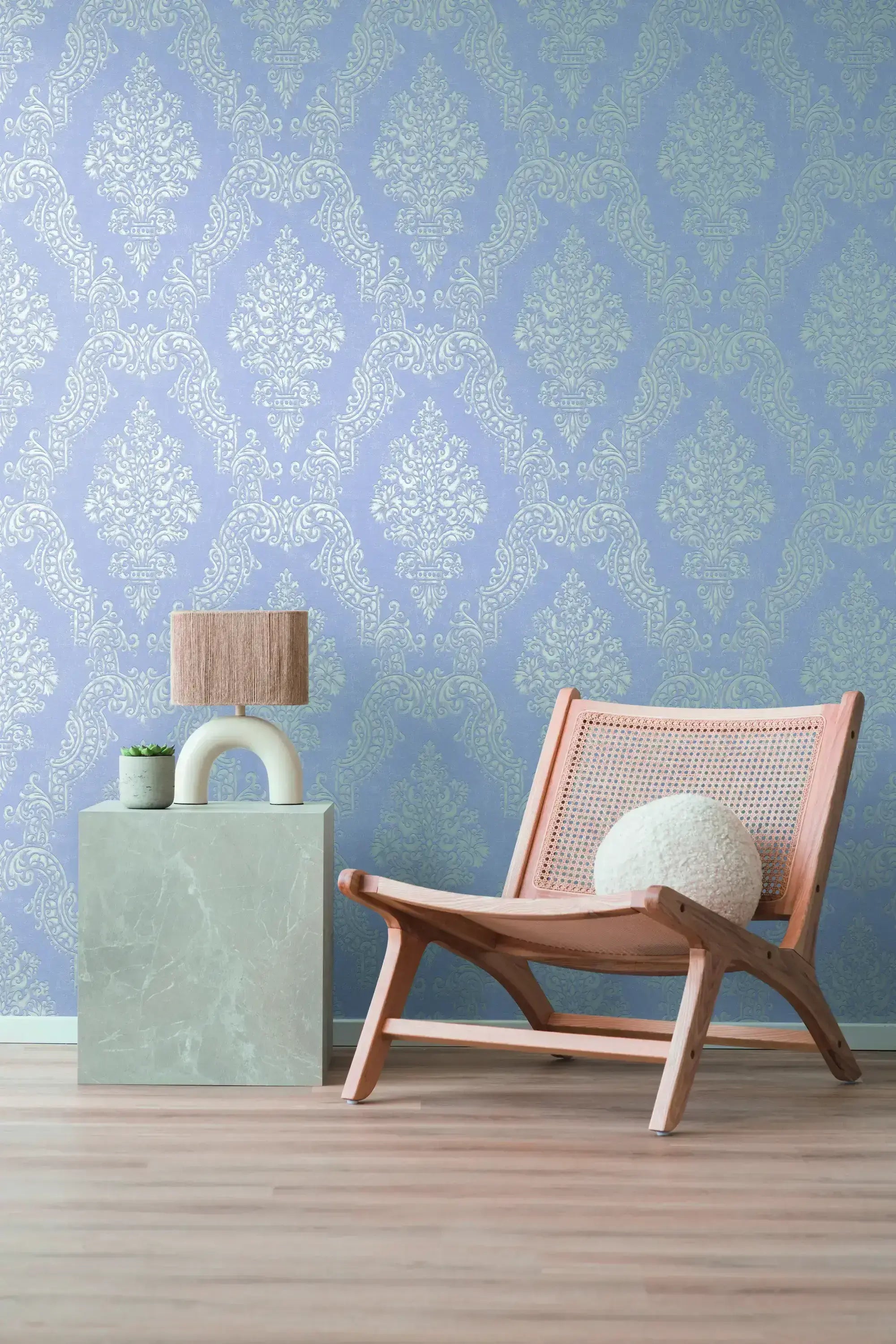 Moderne interiør med Baroque Elegance - Cerulean tapet som baggrund, der viser et barok mønster i blå nuancer. Inkluderer en stol, en bordlampe og en plante.