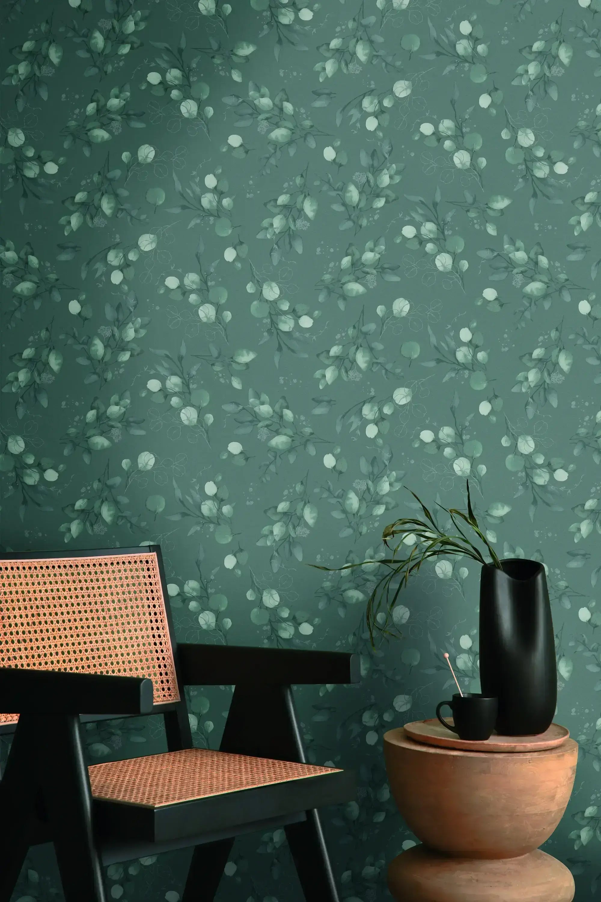 Værelse dekoreret med Botanic Elegance - Mist tapet, inklusiv en stol med flettet sæde og et bord med en sort vase.