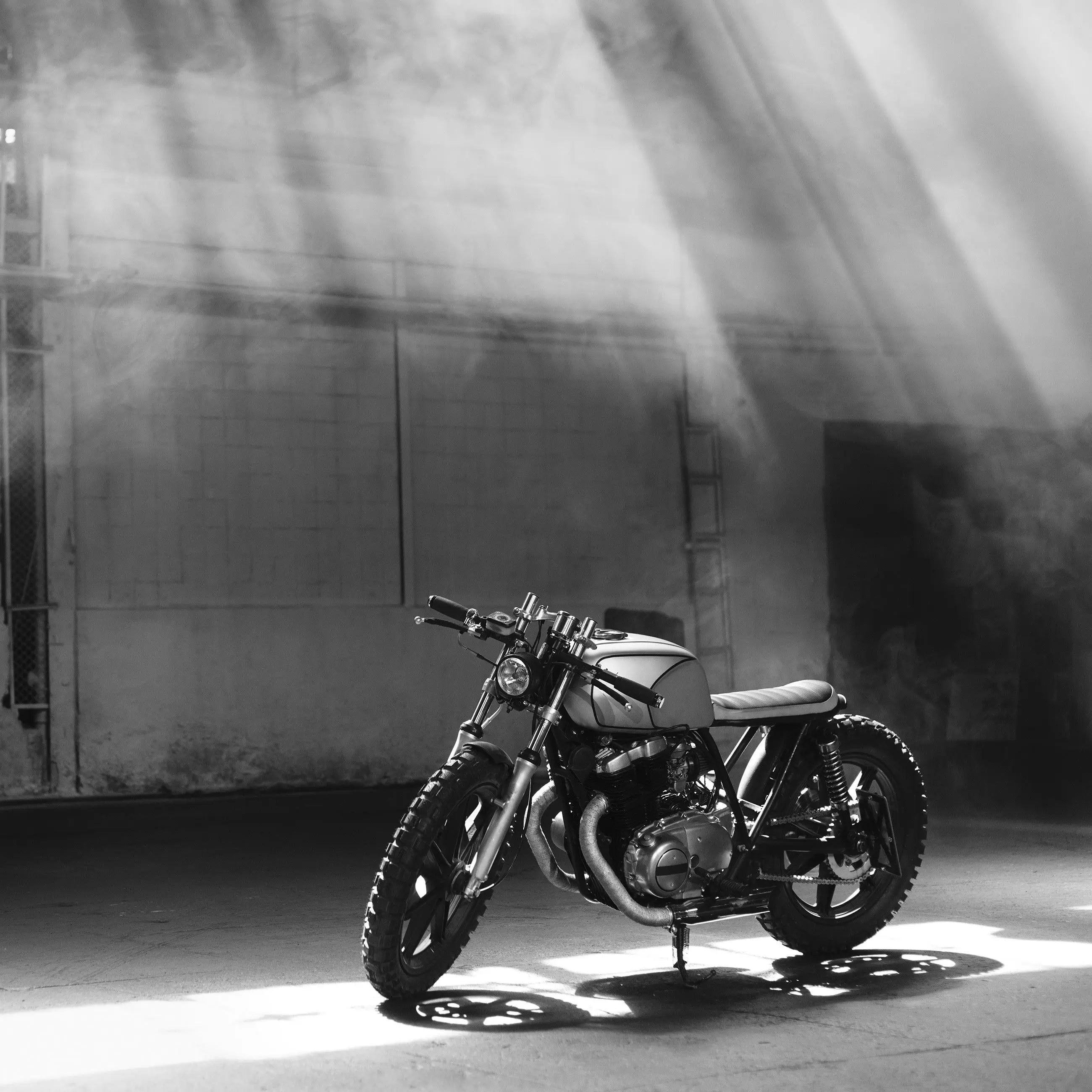 Billede 13 af Fototapet - Café racer motorcykel i solstråler i industriel hal