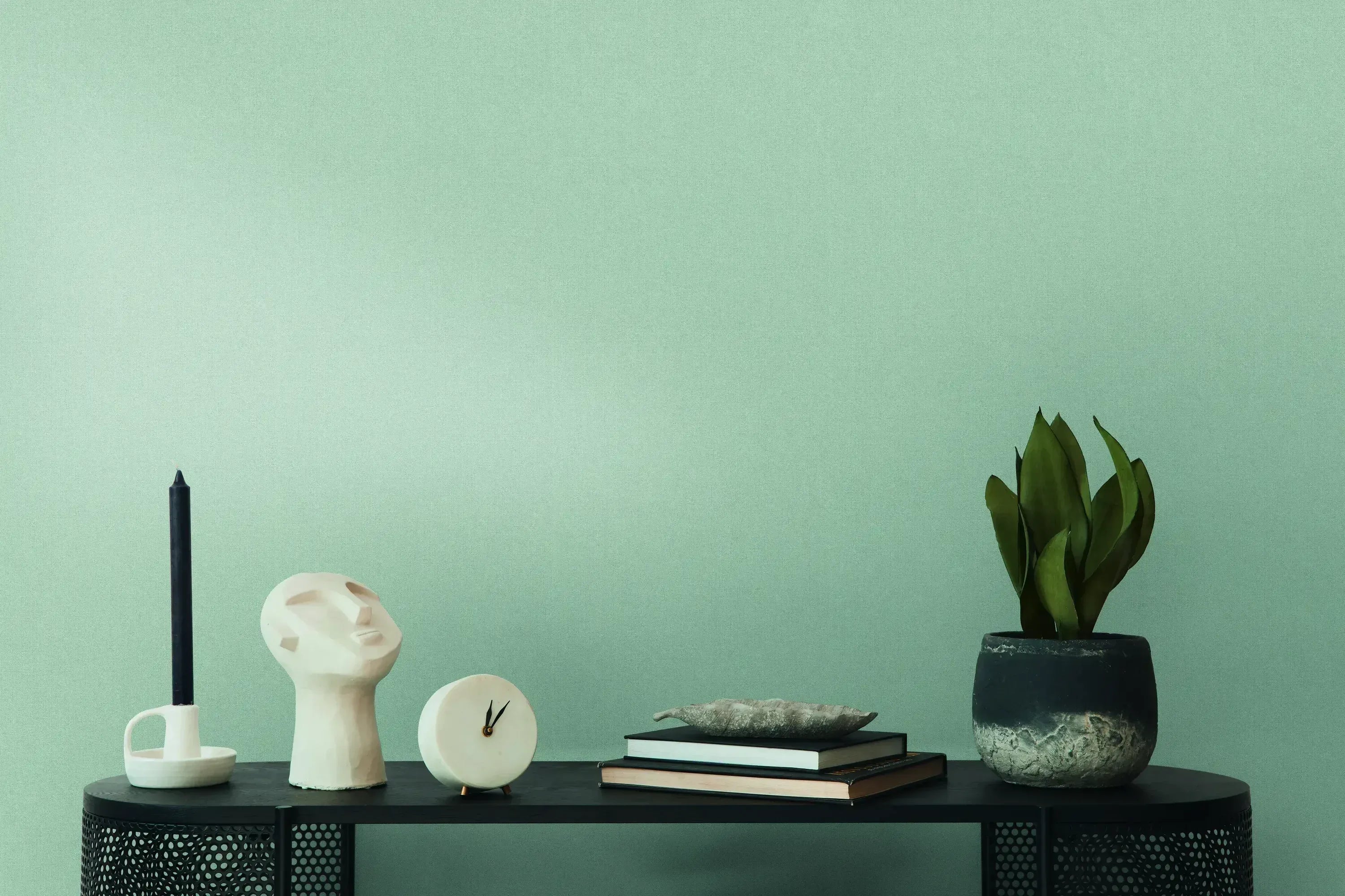 Indretning med tapet Linen Elegance - Smoke fra Nicetapet.dk. Røgfarvet baggrund med dekorative genstande på en hylde, herunder en plantepotte, bøger og skulpturel kunst.