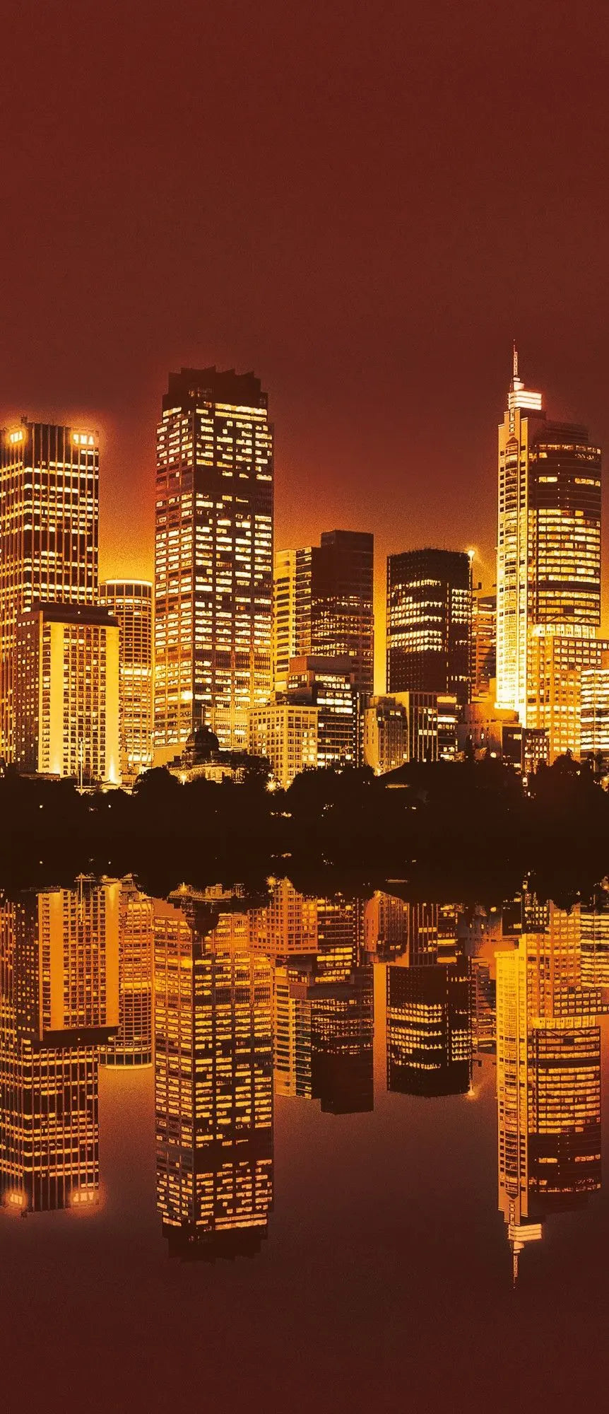 Billede 9 af Fototapet - Oplyst skyline med vandrefleksion ved solnedgang