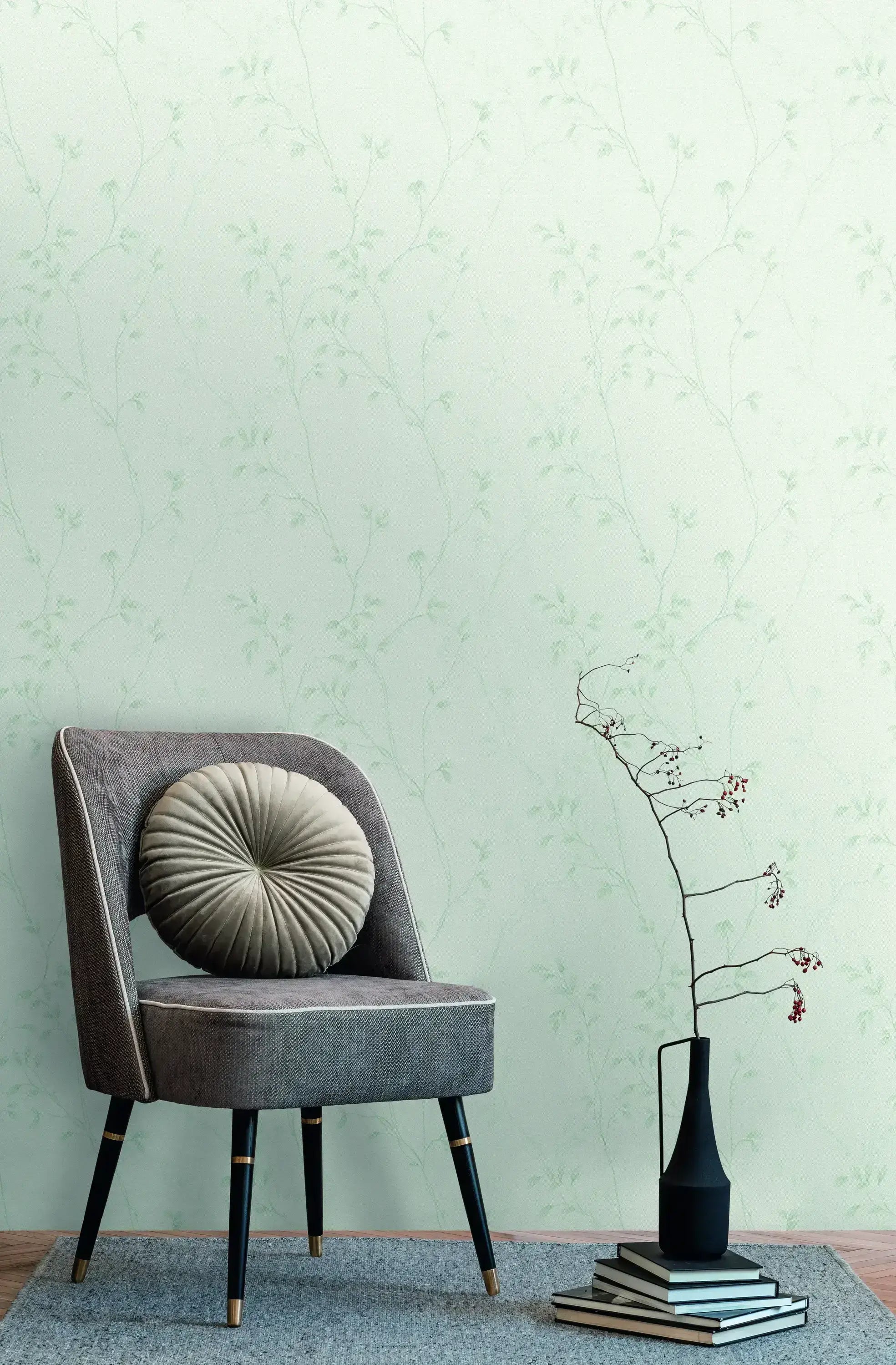 Interiør med Vineyard Elegance - Mint tapet på væggen, en grå stol med en rund pude og en vase med en gren på gulvet.