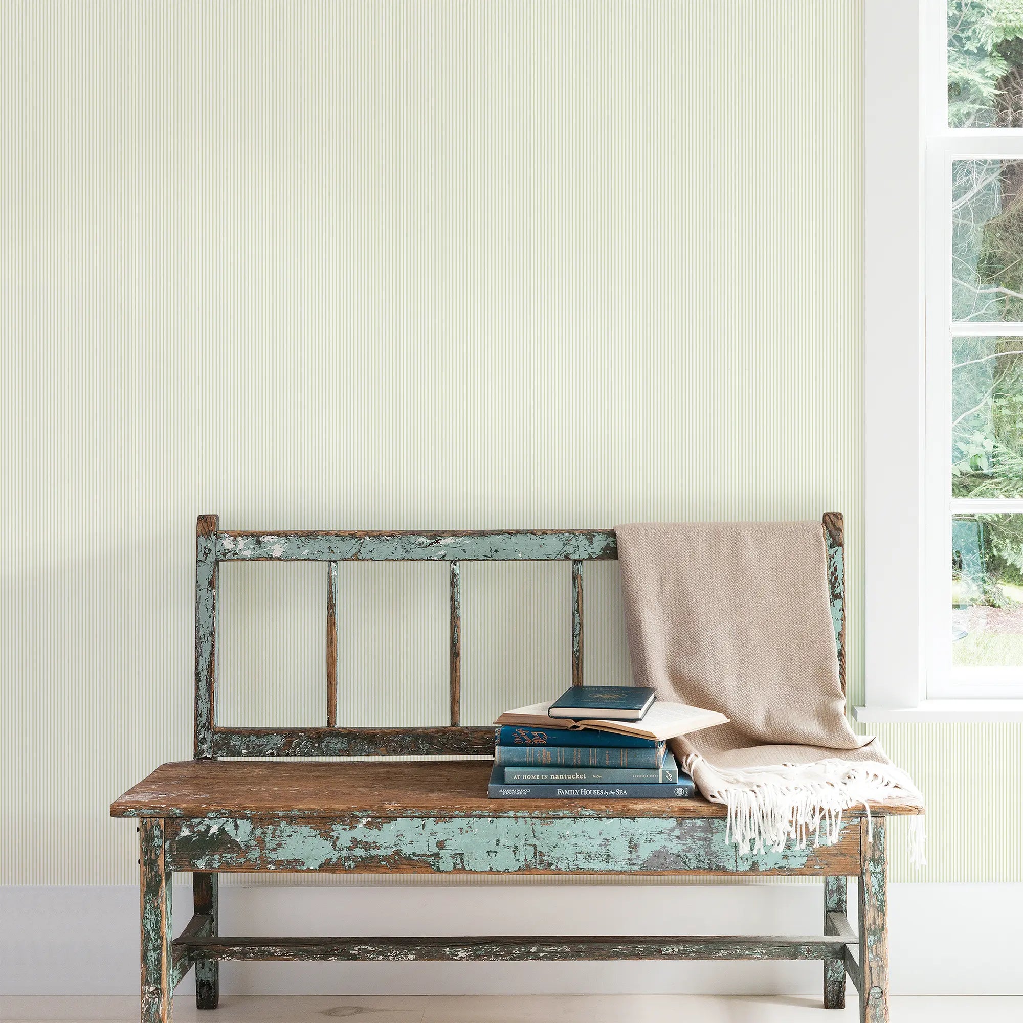 Interiør med Delicate Stripes - Mint tapet fra Nicetapet.dk, der viser en gammel bænk foran en væg, dekoreret med smalle, lysegrønne striber og et vindue til højre.