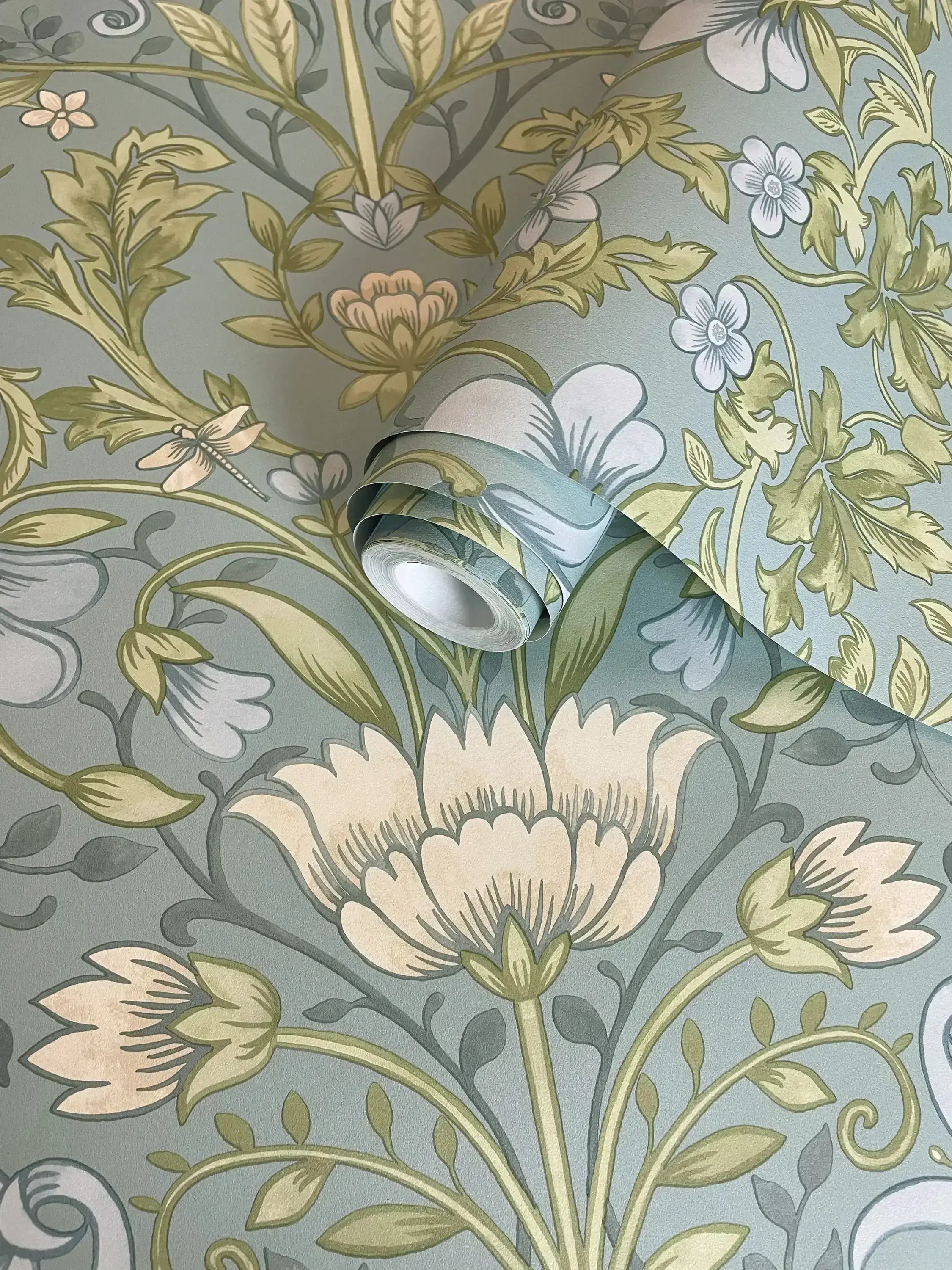 En rulle Emiliana - Soft Blue tapet fra Nicetapet.dk med blomstermønstre synlige i nærbillede.