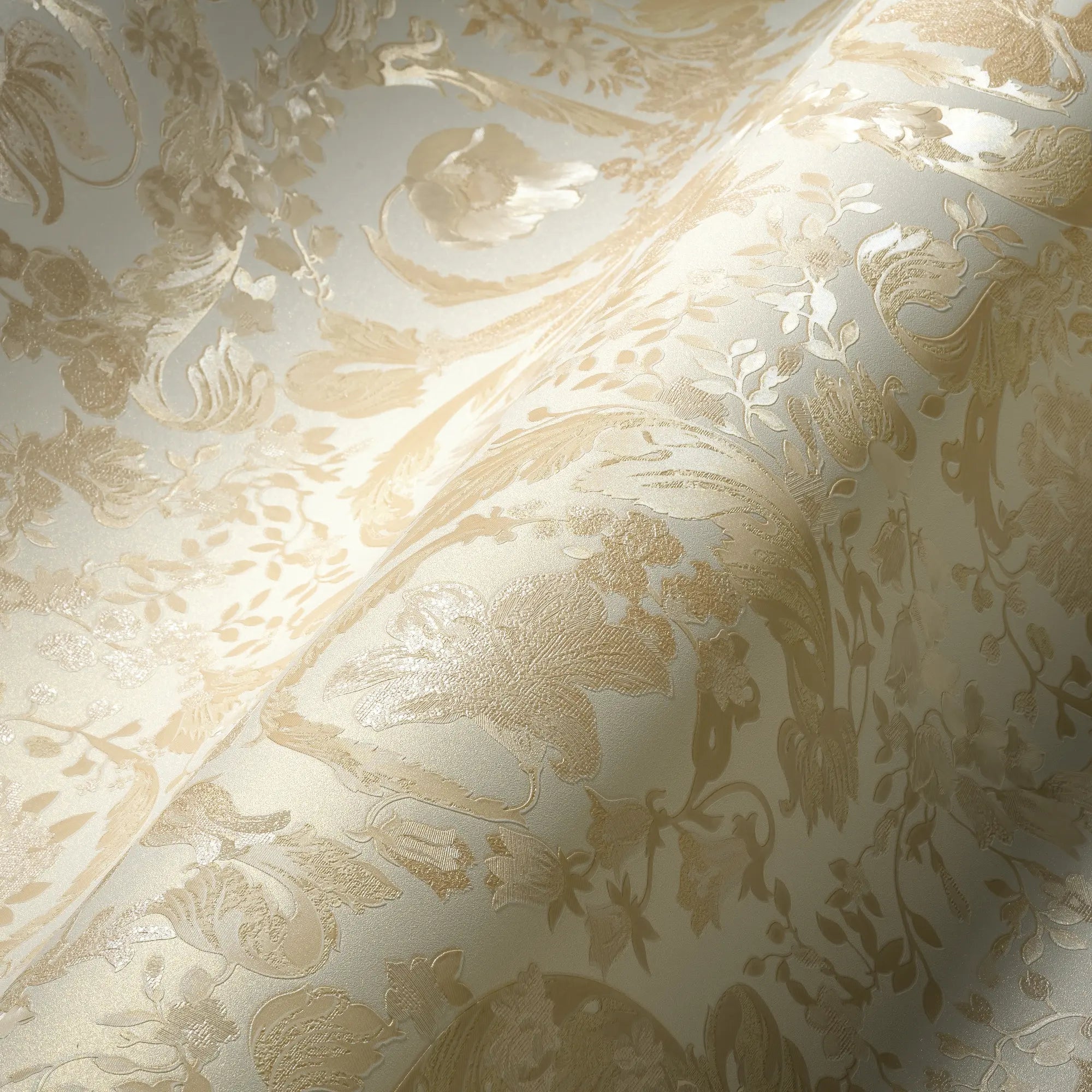Nærbillede af Versace Virtus Heritage - Muted Gold tapet, der fremhæver den rige tekstur og det elegante blomsterdesign i guld.