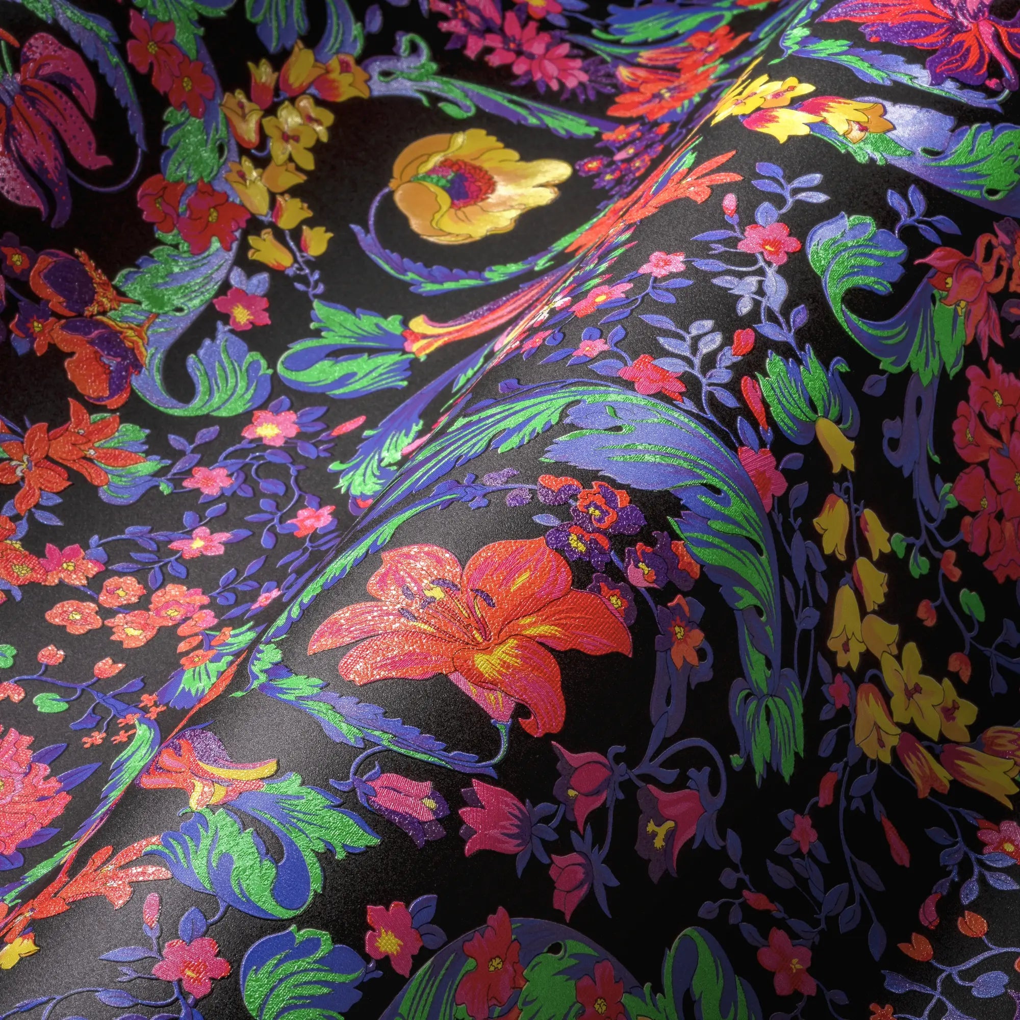 Nærbillede af Versace Virtus Heritage tapet med detaljerede blomster i levende farver på bølgende sort baggrund.
